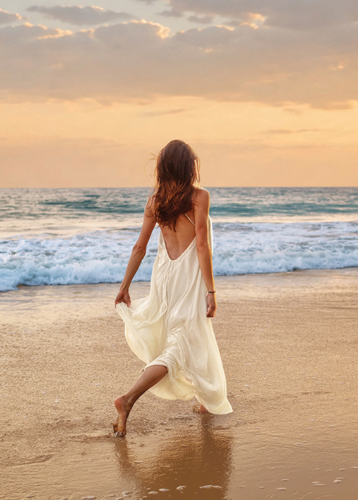 A woman walking along the shoreline at golden hour