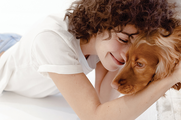 A woman lying down and cuddling her dog